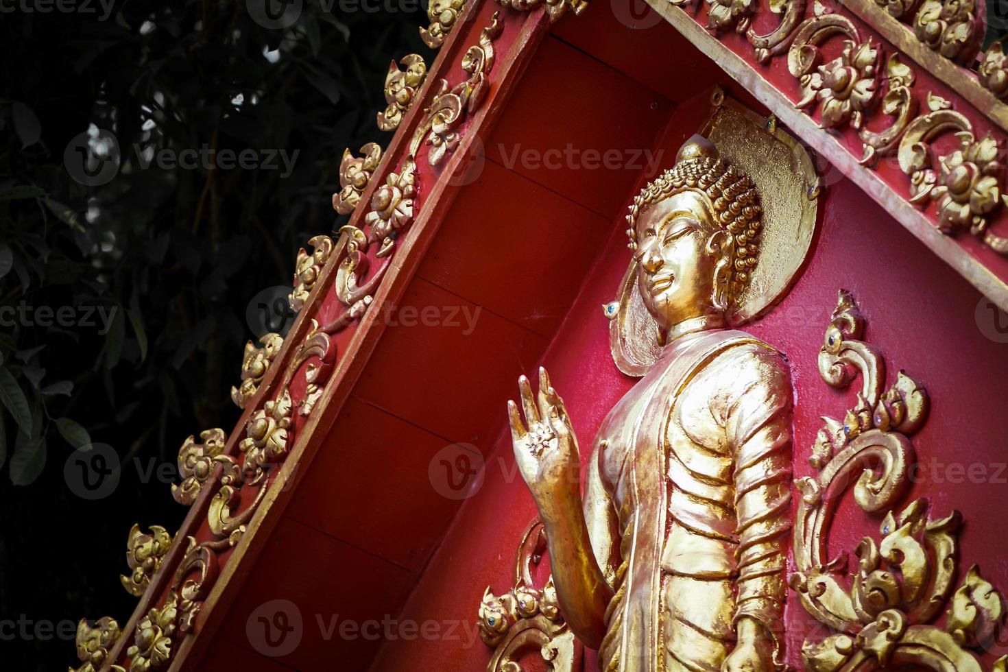 grande statua di buddha d'oro con parete di fondo rossa. foto