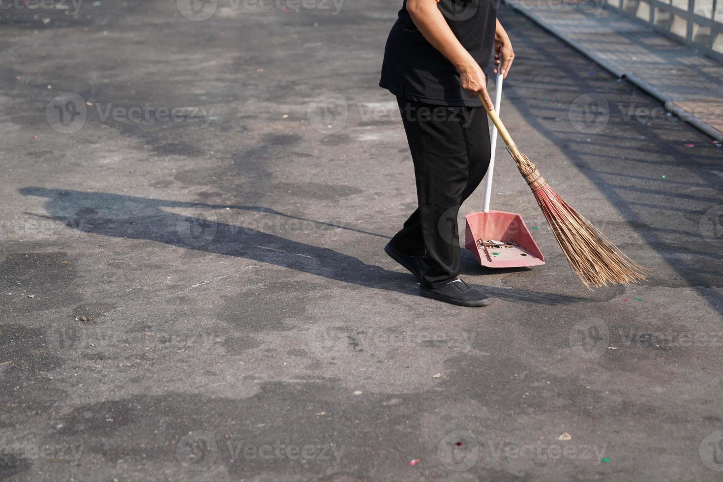 più pulito spazzare la spazzatura in un'ampia area all'aperto di asfalto a mezzogiorno. foto
