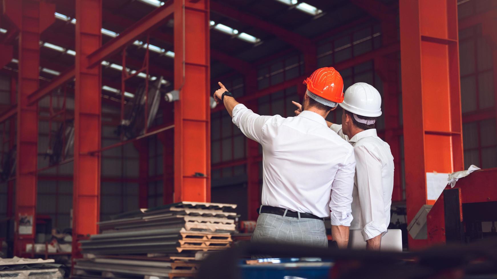 caposquadra operaio e direttore tecnico che lavorano insieme nel cantiere industriale, indossando elmetto per sicurezza foto