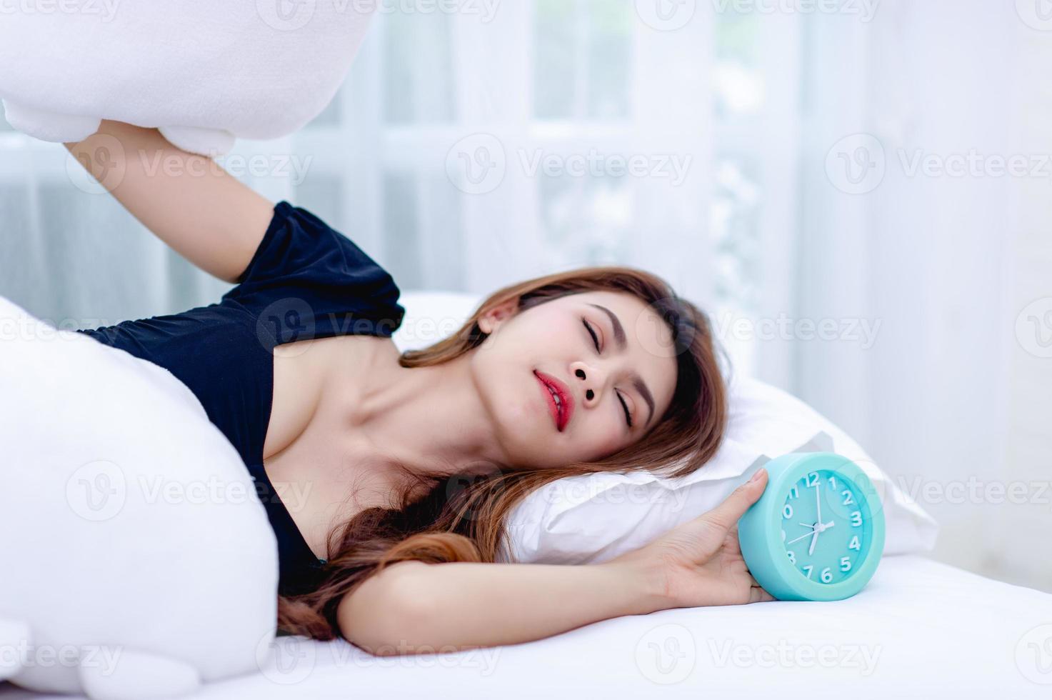 la donna ha tolto il cuscino dall'orecchio mentre al mattino suonava la sveglia. l'idea di svegliarsi per andare al lavoro in orario foto
