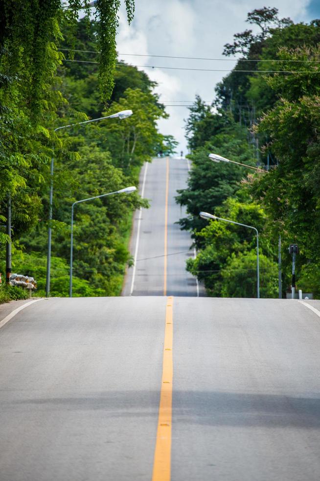 la bella lunga strada che attraversa la foresta nella campagna della Thailandia. foto