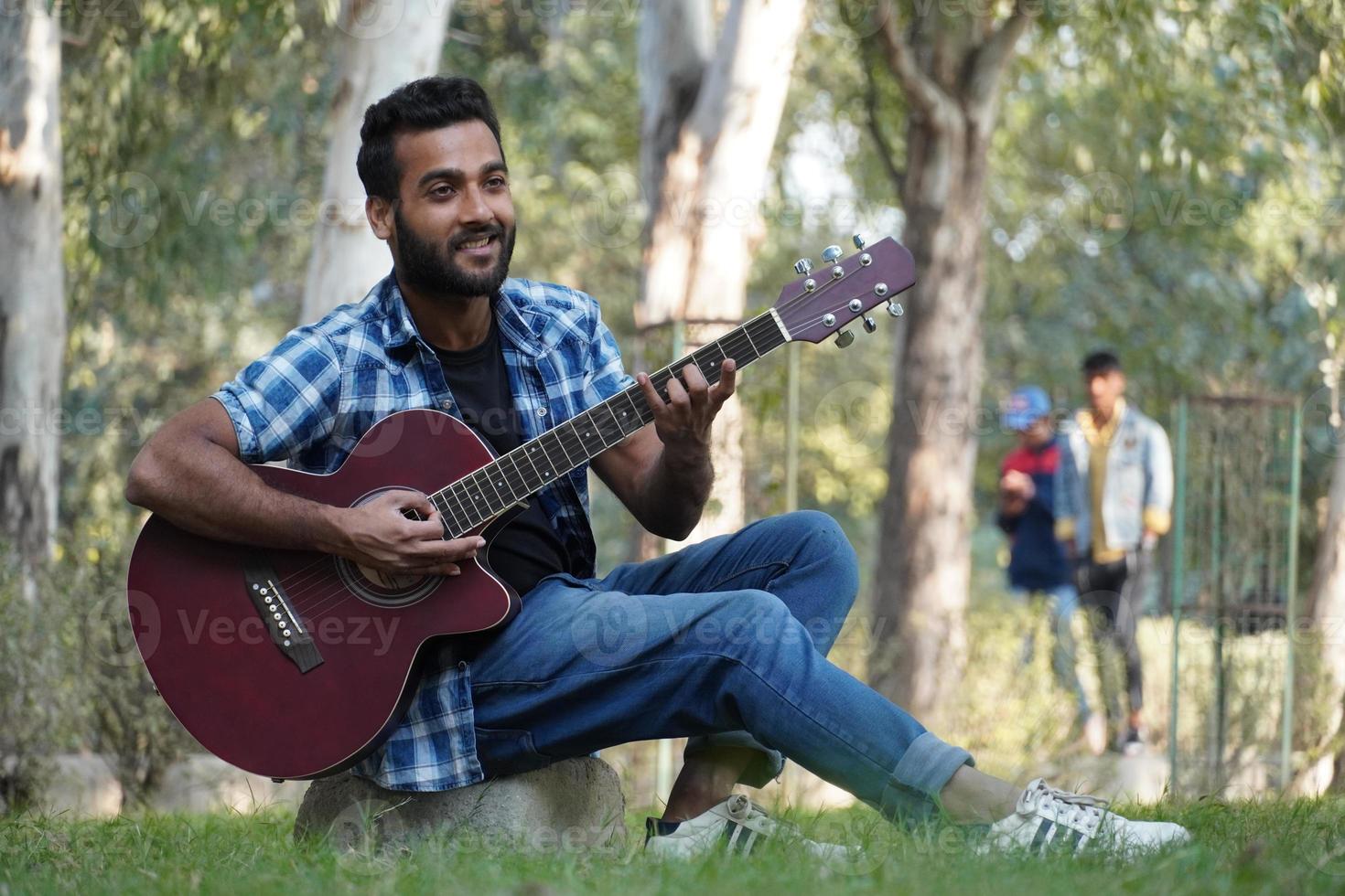 ragazzo con la sua chitarra e suonare la chitarra nel parco foto