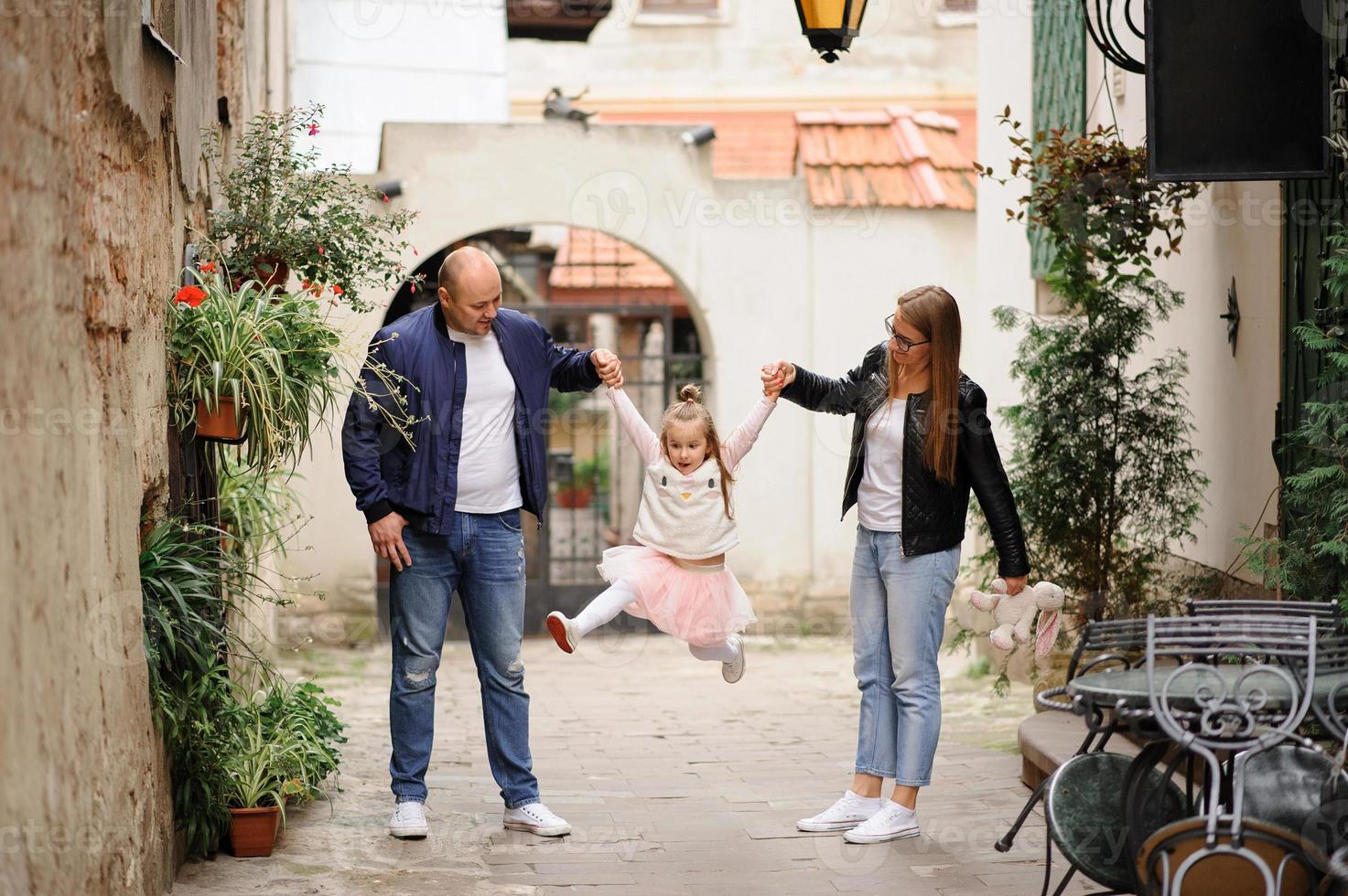 i genitori e la figlia sono seduti sui gradini di una vecchia chiesa. foto