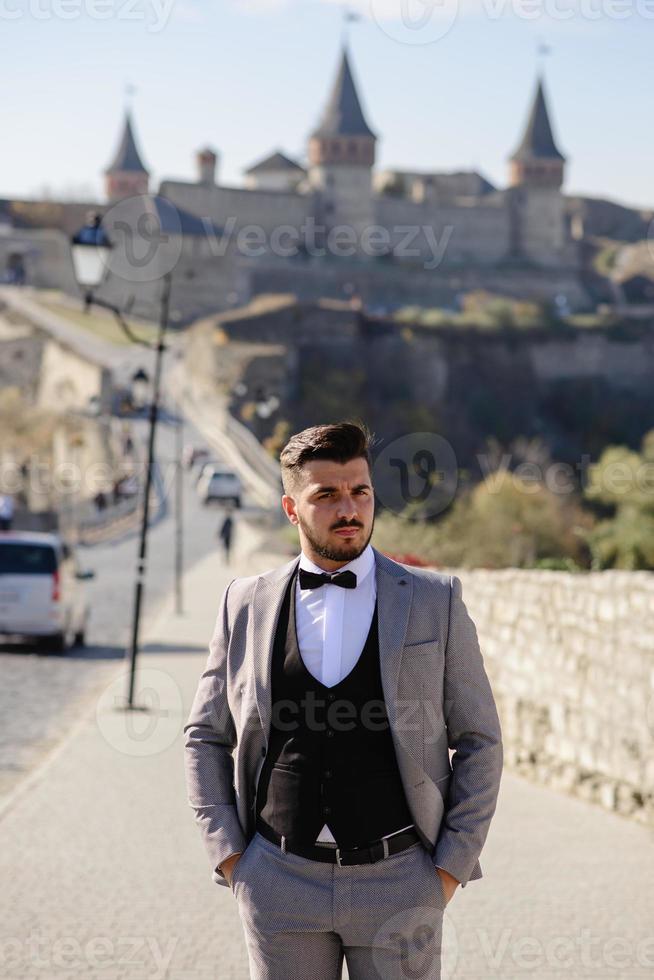 gli sposi stanno passeggiando vicino al vecchio castello. la coppia sta con le spalle l'una all'altra. foto