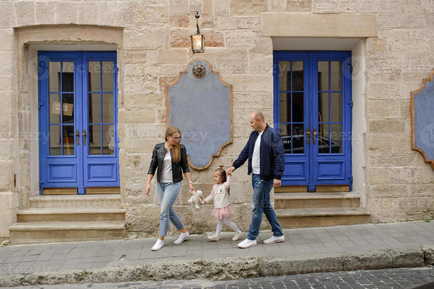 i genitori e la figlia sono seduti sui gradini di una vecchia chiesa. foto