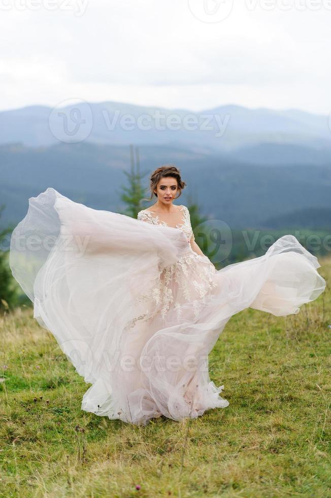 la sposa in un vestito rosa arioso volteggia e gioca con il suo vestito. foto