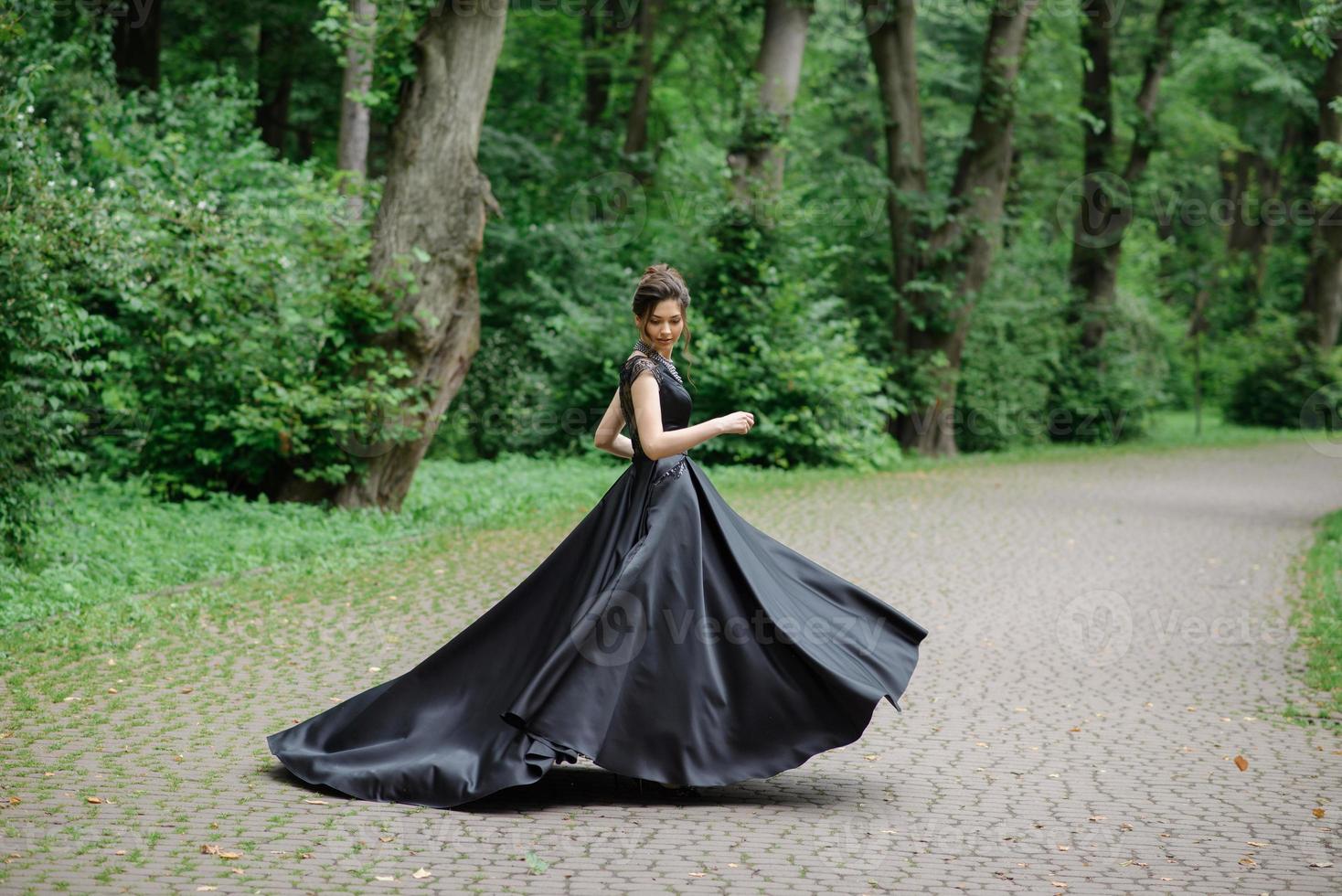 giovane bella donna che posa in un vestito nero in un parco. foto