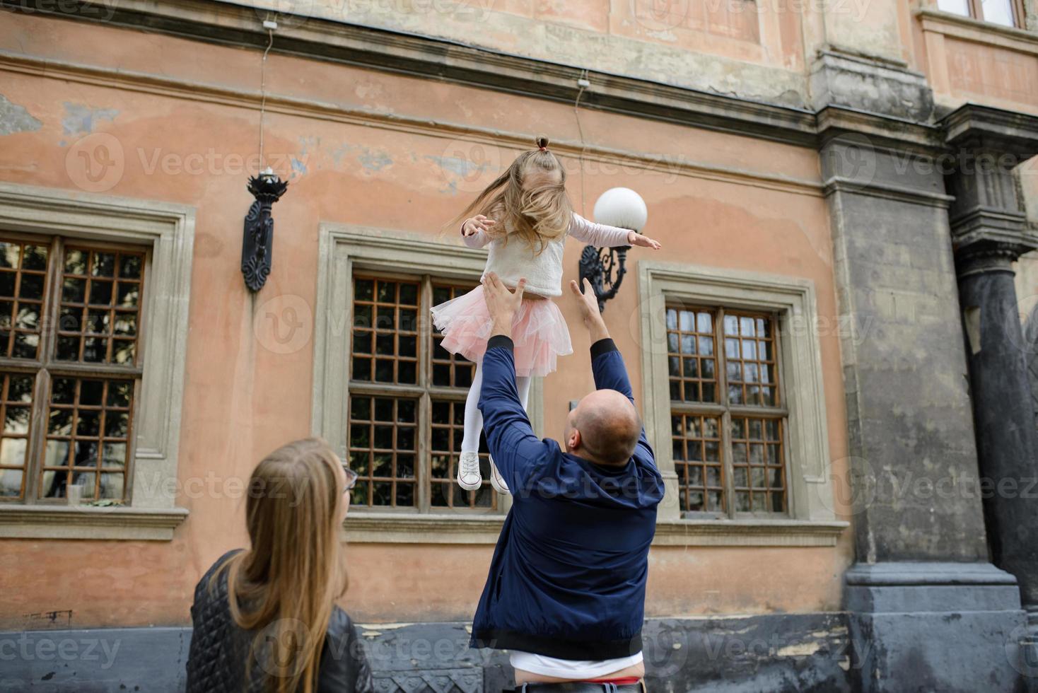 i genitori e la figlia sono seduti sui gradini di una vecchia chiesa. foto