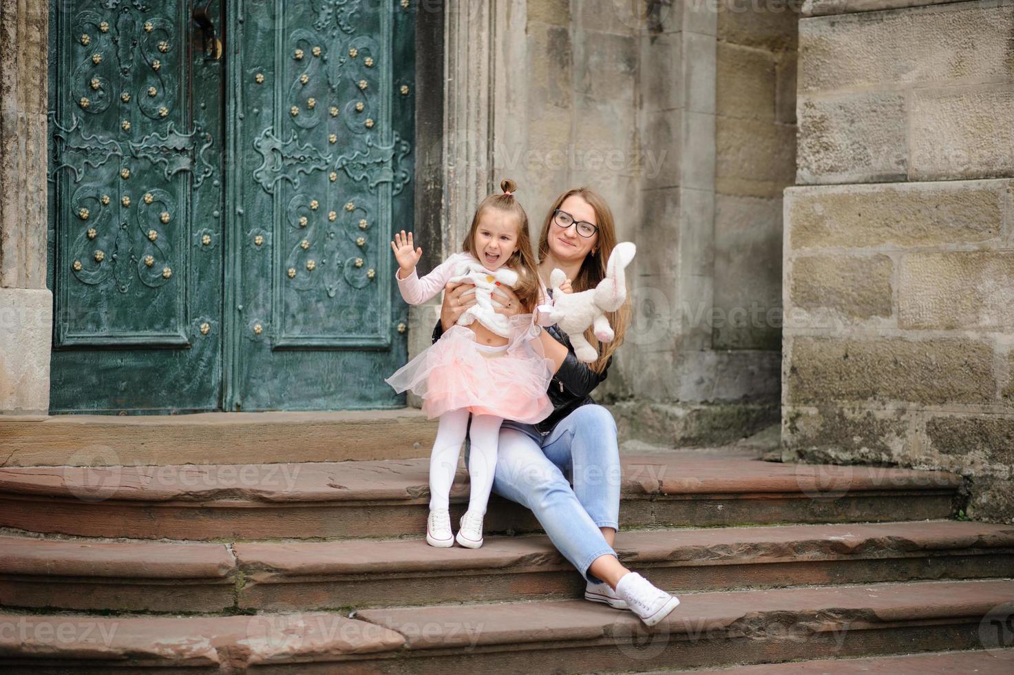 i genitori e la figlia sono seduti sui gradini di una vecchia chiesa. foto