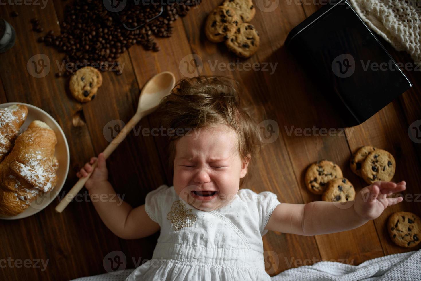 la bambina cuoca con un cucchiaio di legno sta preparando il pranzo. foto