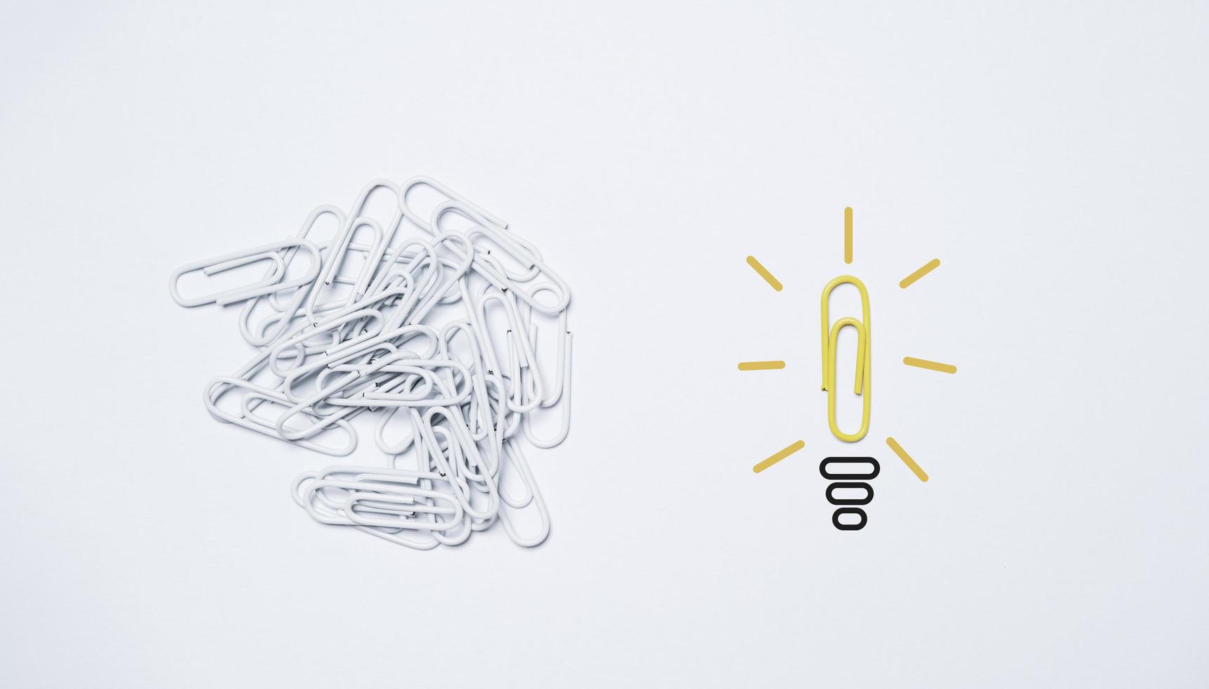 la graffetta gialla si sposta dalla clip bianca e si trasforma in lampadina per il concetto di idea di pensiero creativo. foto