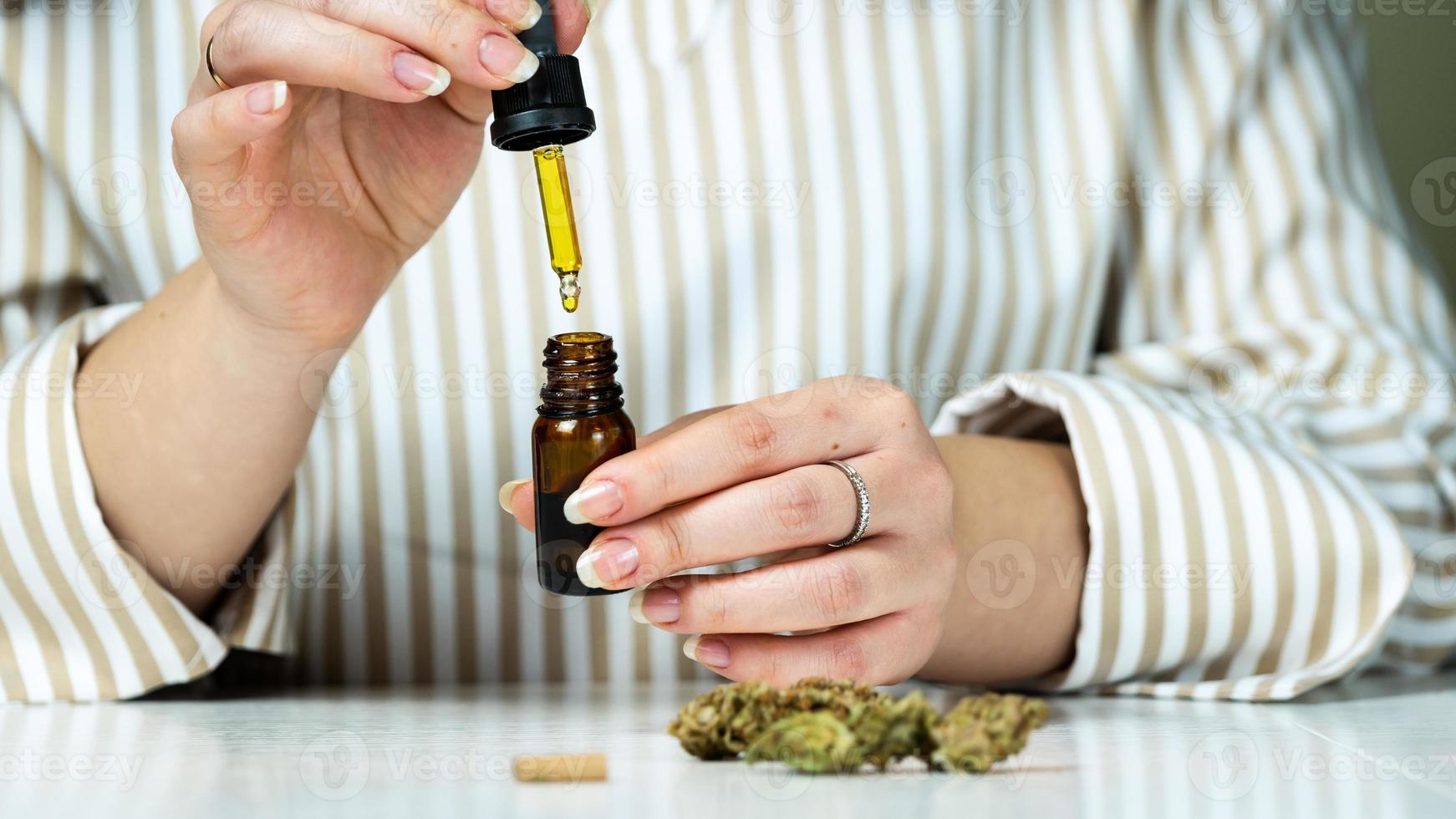 primo piano di una donna irriconoscibile che usa e tiene in mano olio di cannabis medica. foto