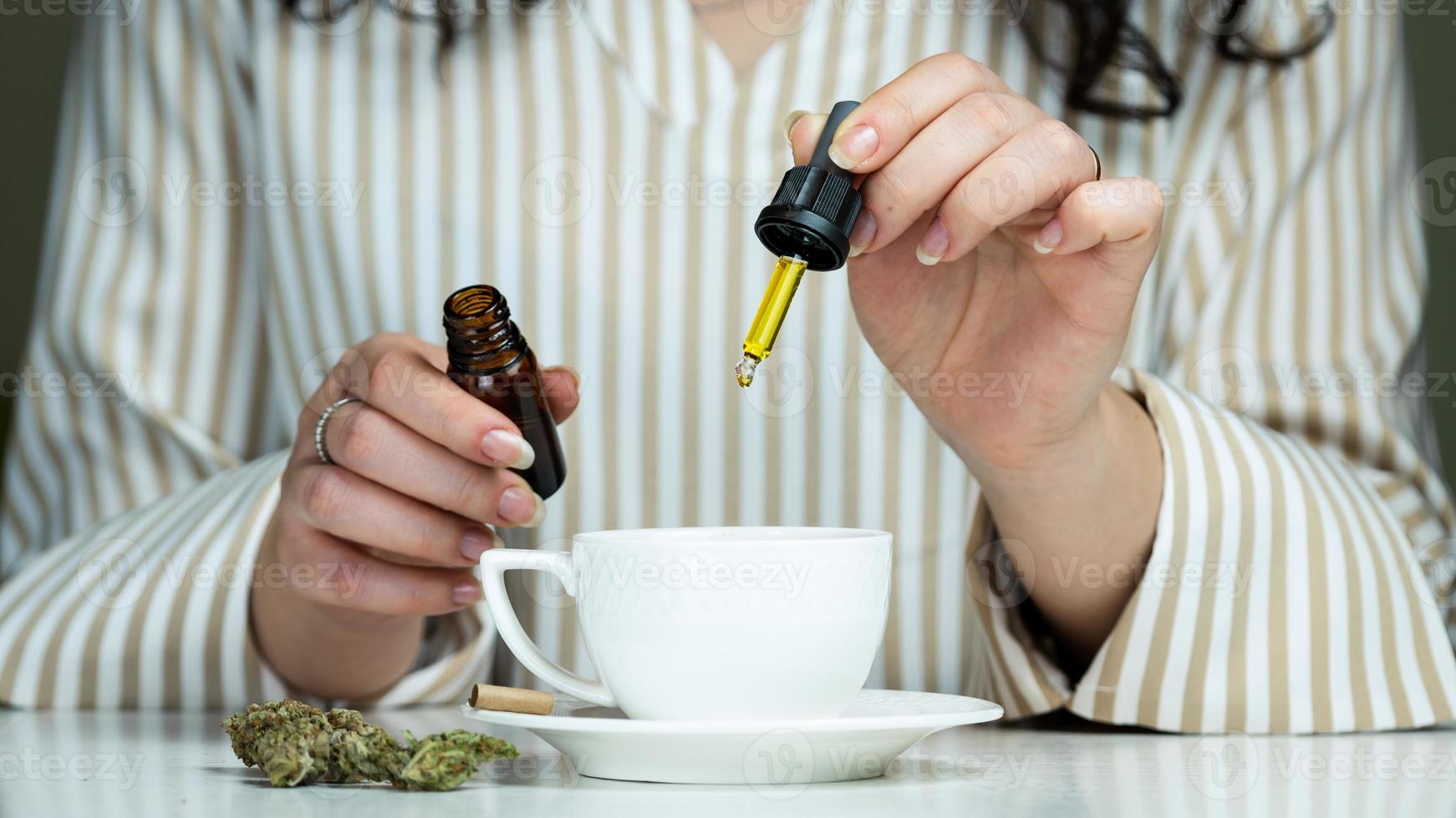 primo piano di una donna irriconoscibile che usa e tiene in mano olio di cannabis medica. foto