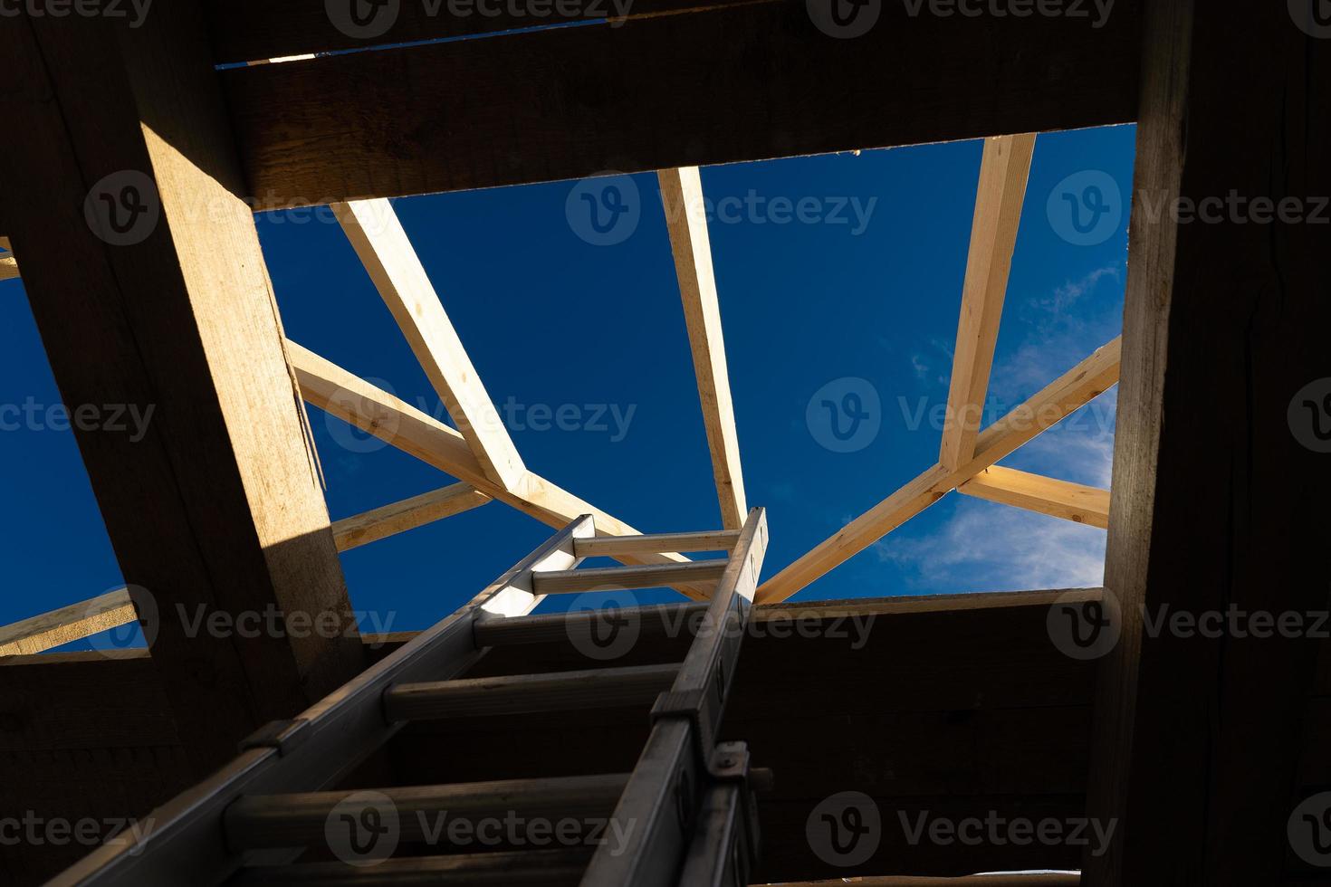 installazione di travi in legno alla costruzione del sistema a capriate del tetto della casa. foto