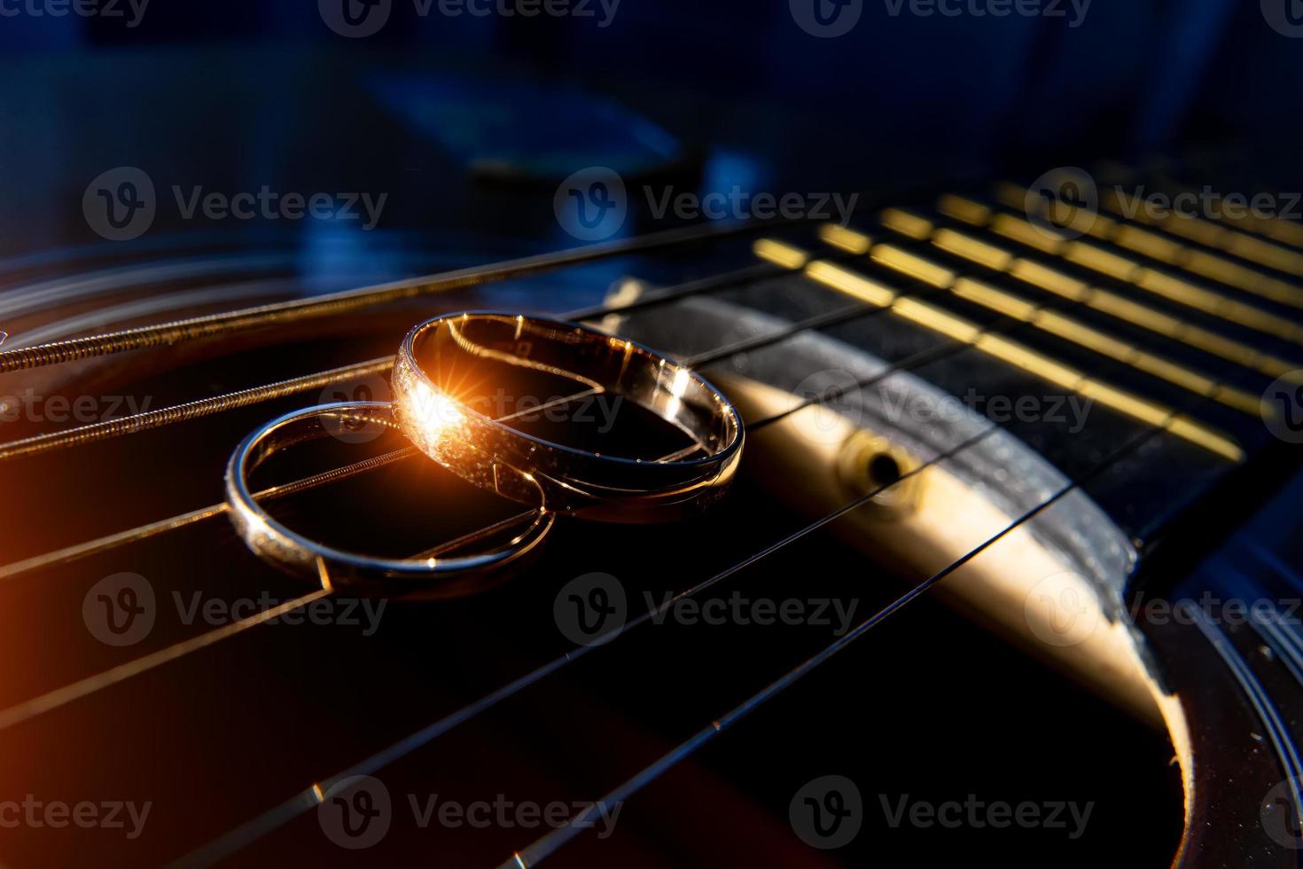 fedi nuziali sul primo piano delle corde della chitarra su uno sfondo scuro. foto