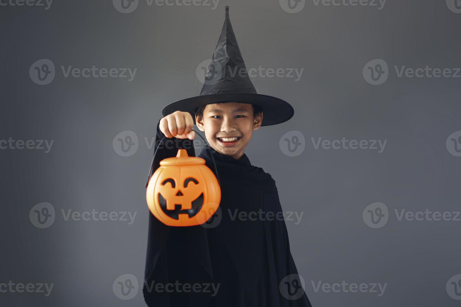 simpatico ragazzo asiatico che celebra halloween indossando un costume da strega e tenendo in mano accessori per la decorazione di halloween foto