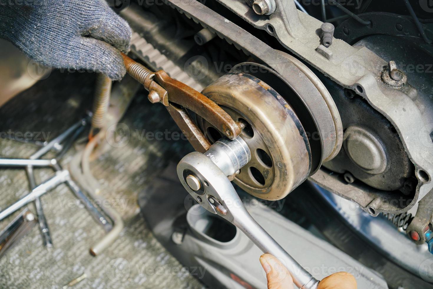 il meccanico utilizza strumenti speciali, chiave inglese per ruota dentata del rotore del mozzo della frizione del volano e sostituisce i dischi della frizione sullo scooter, riparazione e manutenzione del concetto di moto foto