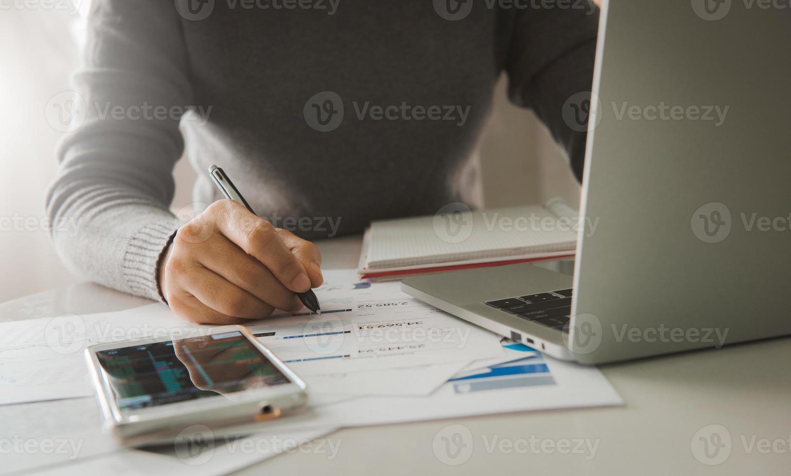 documenti aziendali sul tavolo con smartphone e computer portatile e donna che lavora in background, concetto di economia finanziaria, attività bancarie e ricerche di mercato azionario. foto