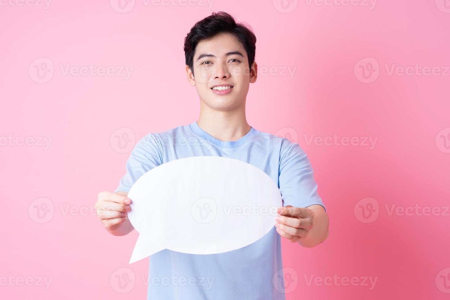 immagine del giovane uomo asiatico che tiene la bolla del messaggio su sfondo rosa foto