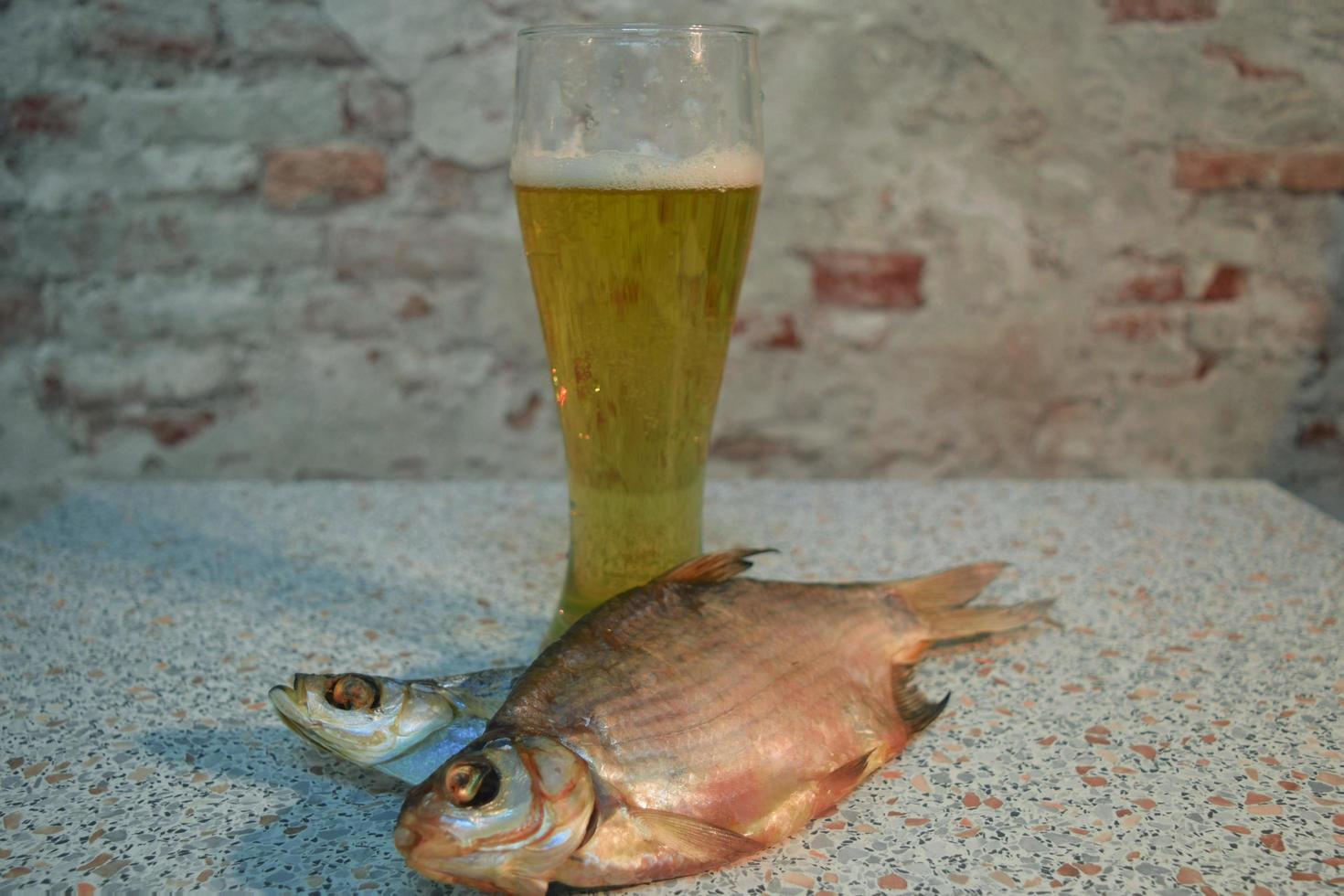 un bicchiere di birra chiara fresca con pesce essiccato foto