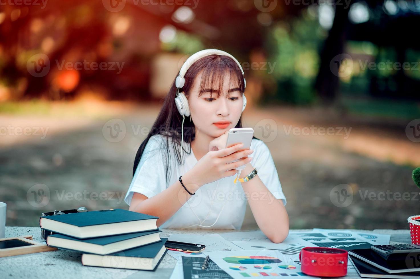 ascoltare la musica. una bella donna con le cuffie si sta rilassando sulla sua scrivania. sorridere e meditare meditazione sta ascoltando musica usando il suo smartphone, concetto di relax e relax. foto