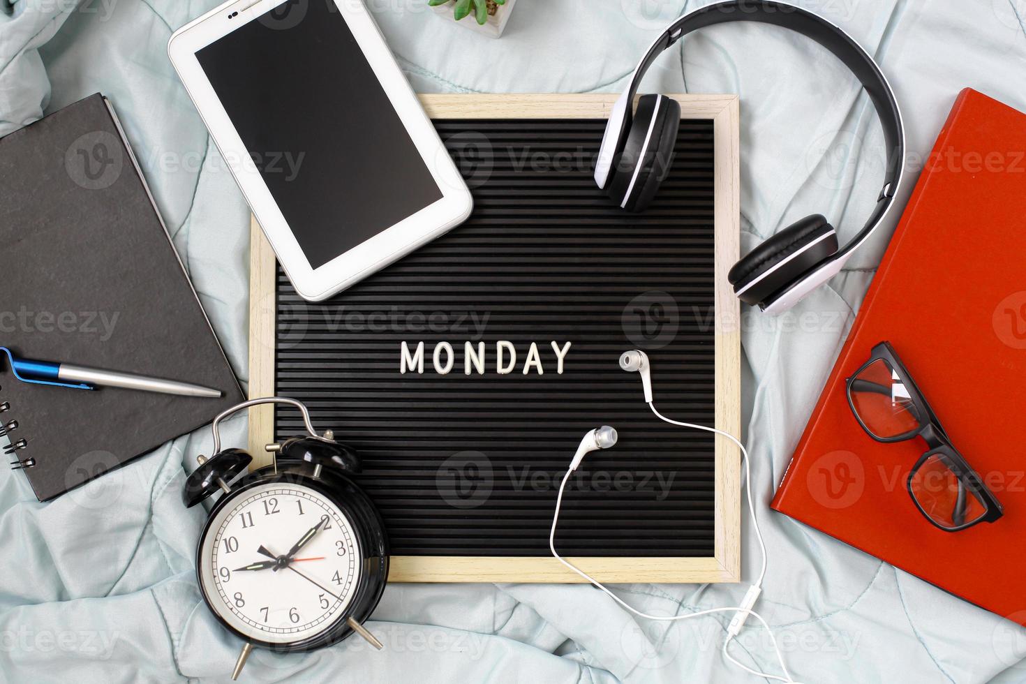 lunedì concetto piatto con accessori multimediali, libri e penne, libri e occhiali, sveglia e caffè per il riposo su sfondo bianco foto