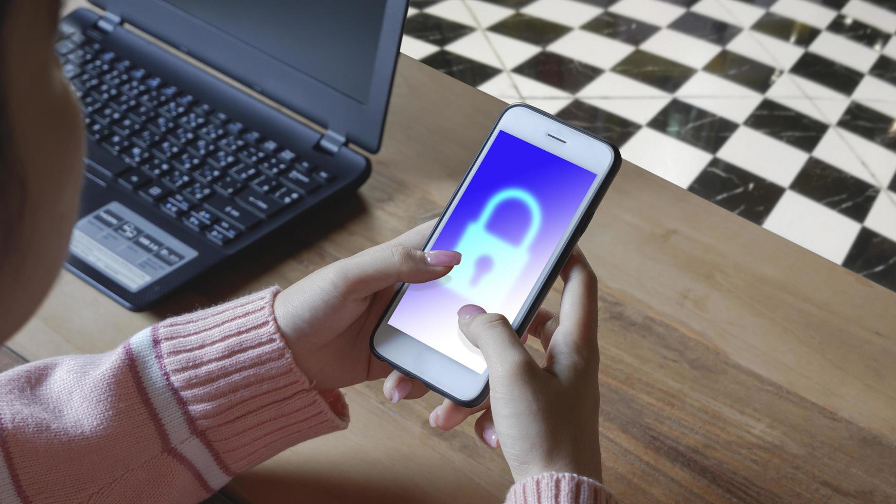 giovane donna che utilizza smartphone nella stanza dell'home office. accedi all'app mobile con il sistema di sicurezza del segno di blocco sullo schermo, la sicurezza informatica sul mobile banking e il concetto di social network foto