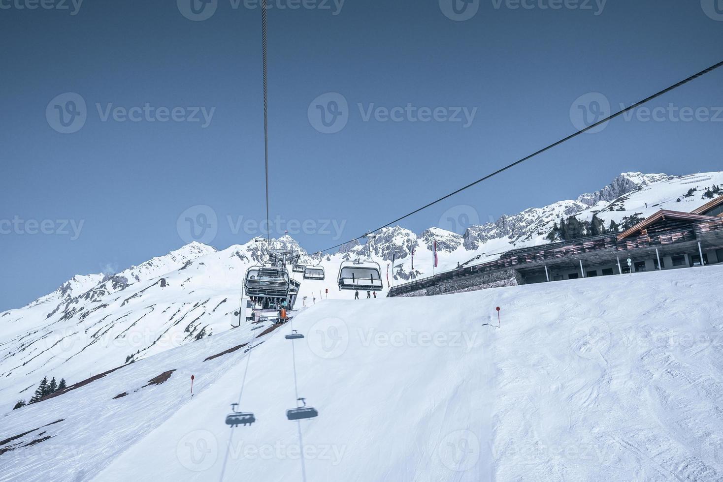 skilift che si muove sopra la catena montuosa innevata contro il cielo limpido foto