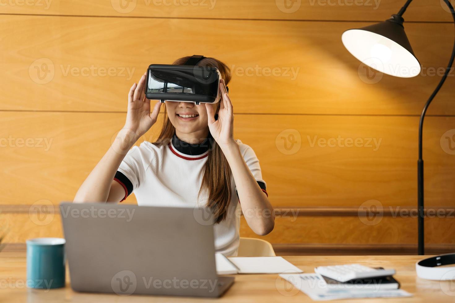 splendida ragazza sorridente indossa un auricolare vr e un tocco interattivo via etere. dispositivo per occhiali con auricolare vr. controllo asiatico della donna d'affari dalla realtà virtuale. foto