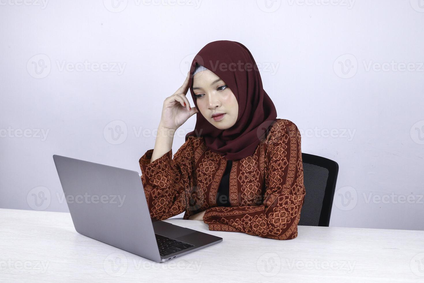 la giovane donna asiatica dell'islam è un aspetto serio con un gesto di pensiero mano sul viso sulla parte anteriore del laptop. foto