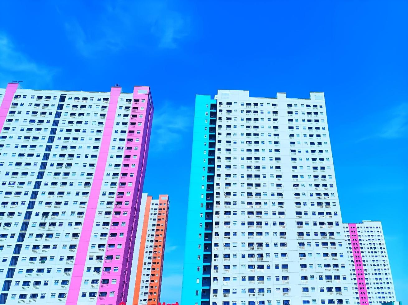 foto di un edificio in bianco brillante, arancione, rosa e blu con molte finestre e anche un cielo blu brillante