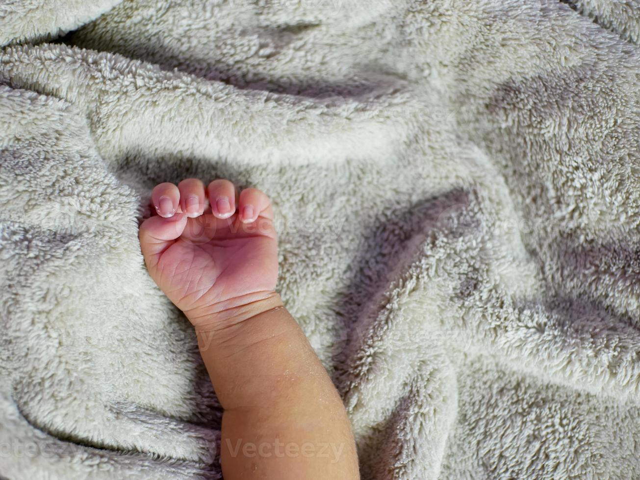 mano del bambino sulla coperta grigia. i neonati si sentono al sicuro e al caldo. messa a fuoco morbida selettiva. foto