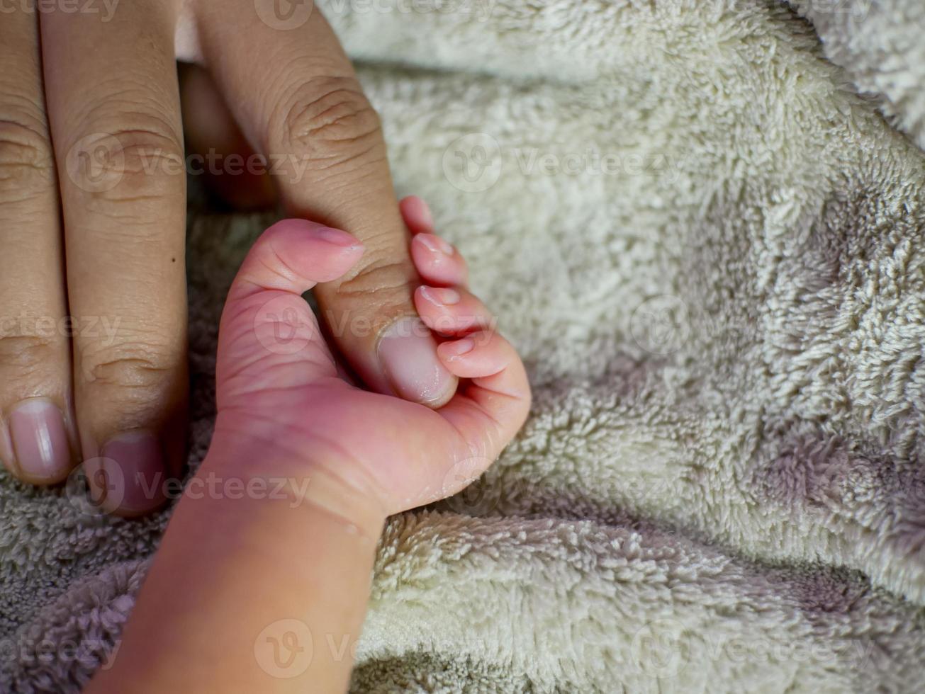 neonato che afferra il dito di sua madre. concetto di cura del bambino, sentirsi al sicuro, amore dei genitori. messa a fuoco morbida selettiva. foto