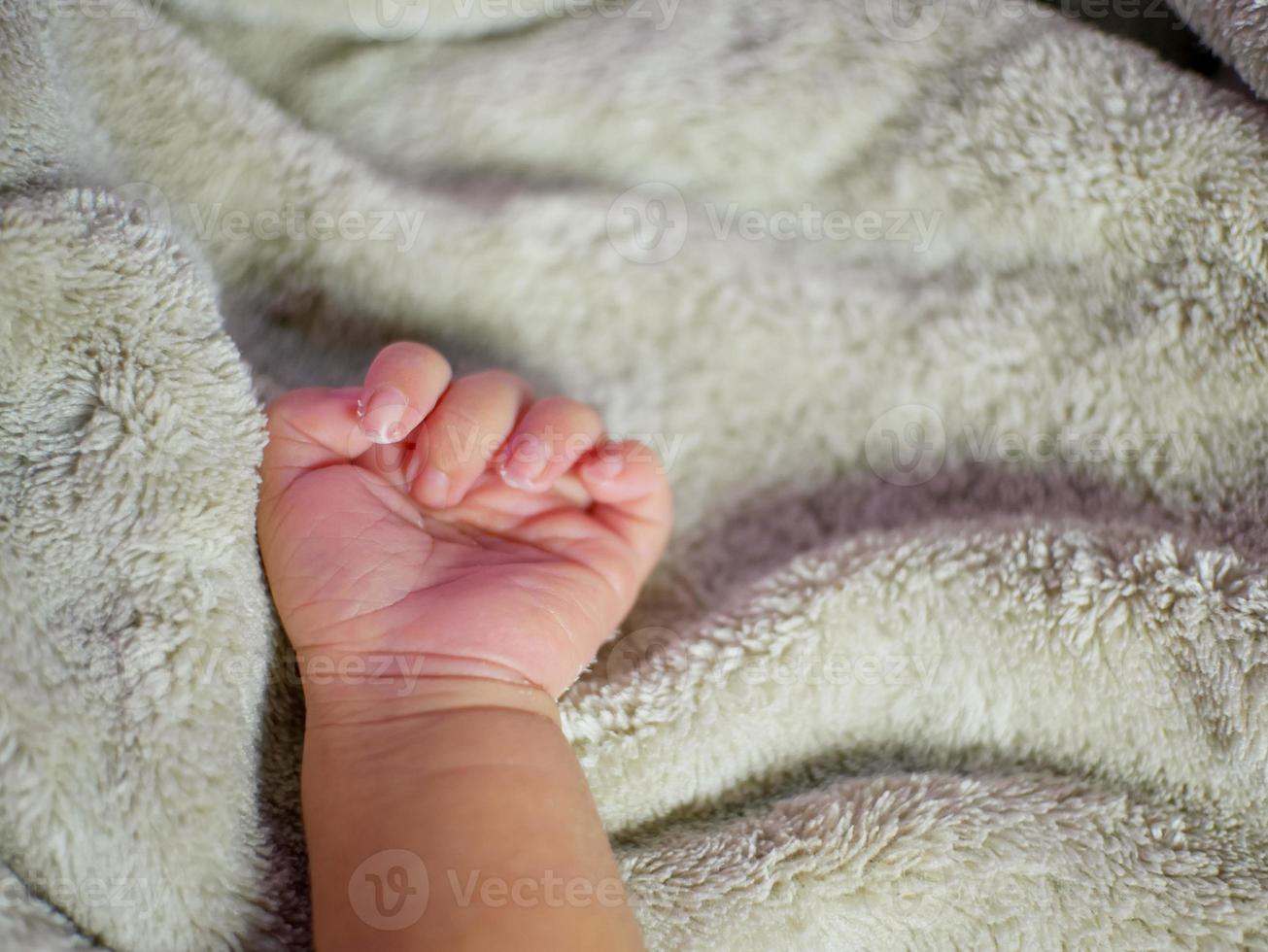 mano del bambino sulla coperta grigia. i neonati si sentono al sicuro e al caldo. messa a fuoco morbida selettiva. foto