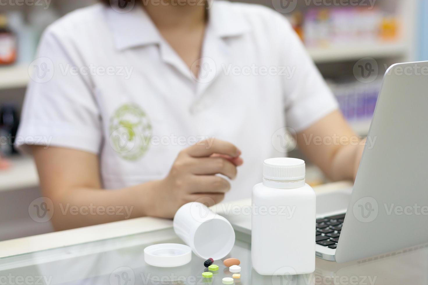 farmacista con computer portatile e farmaci in farmacia foto