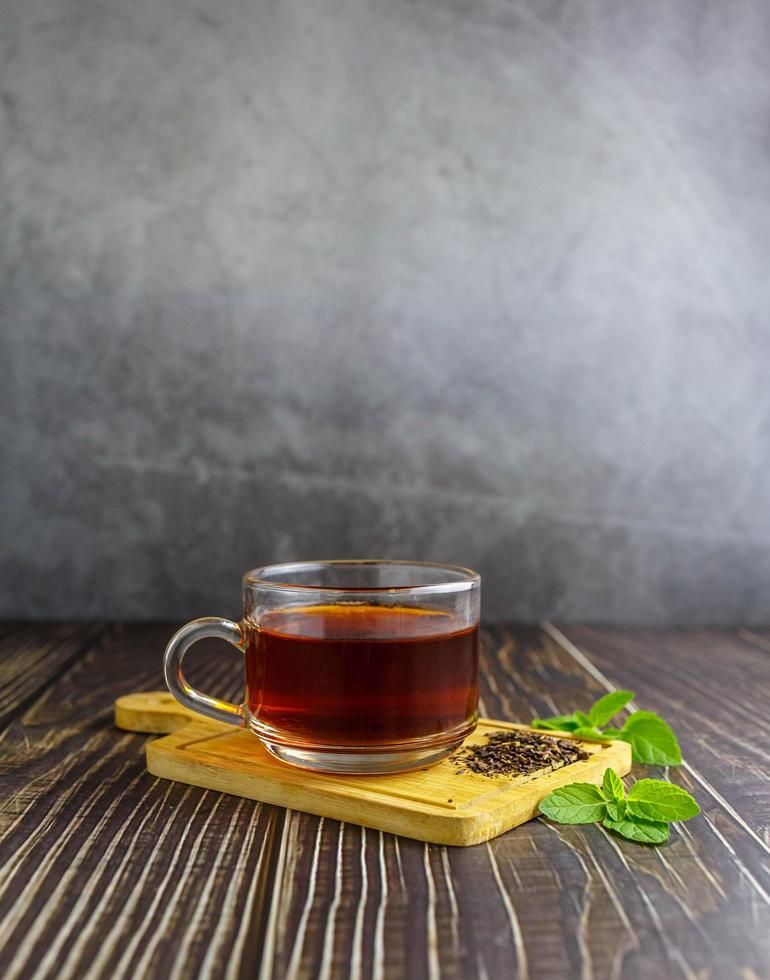 tè in tazza di vetro su fondo di legno foto