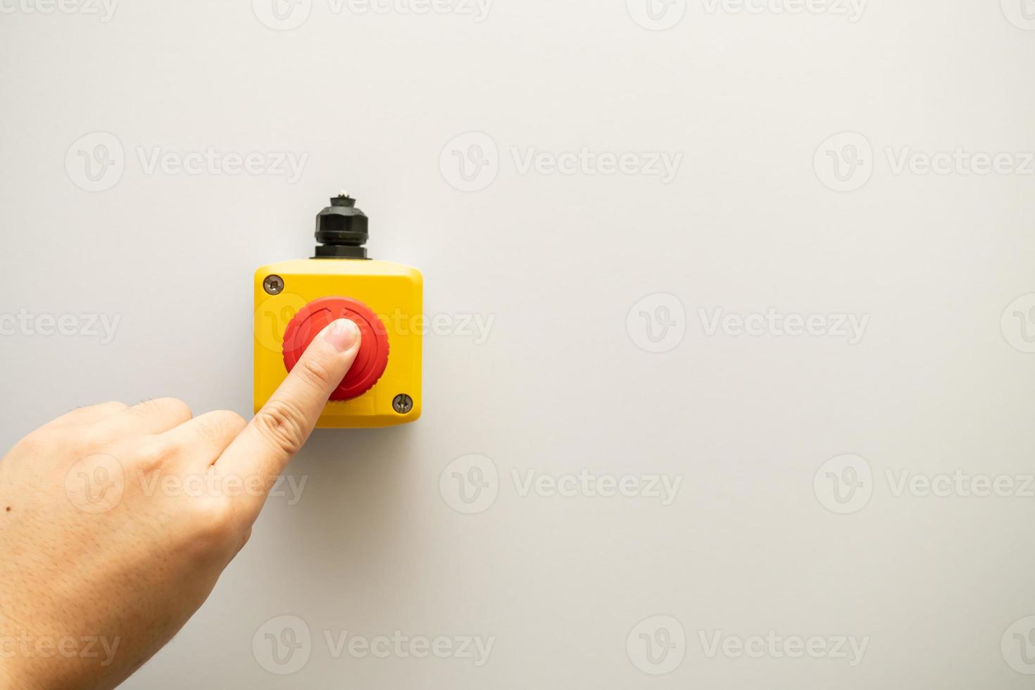 fermare il pulsante rosso e la mano del lavoratore che sta per premerlo. pulsante di arresto di emergenza. grande pulsante rosso di emergenza o pulsante di arresto per la pressione manuale. foto