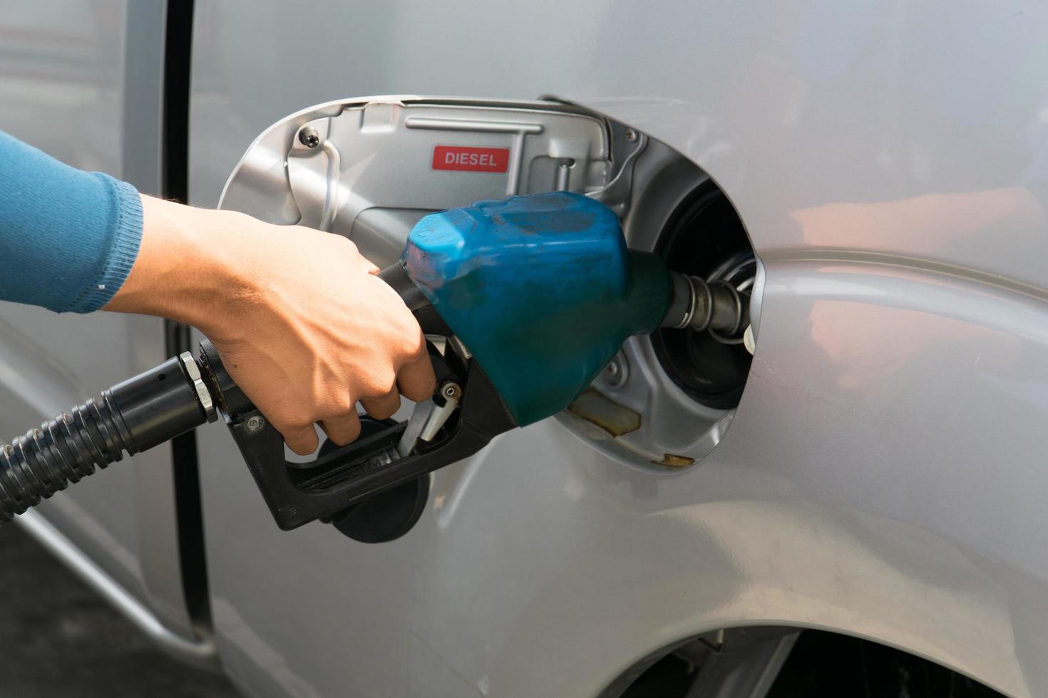 gli uomini tengono l'ugello del carburante per aggiungere carburante in auto alla stazione di servizio foto