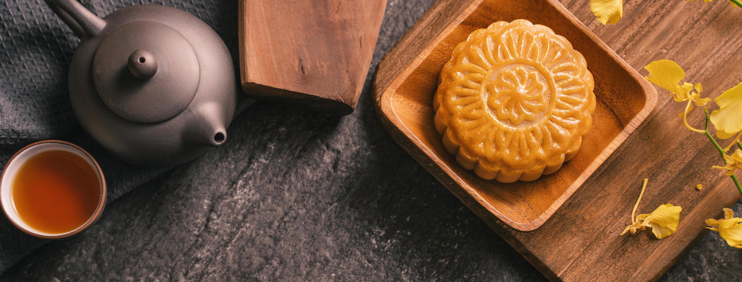 concetto di cibo tradizionale del festival di metà autunno - bella torta lunare su tavolo in ardesia nera con tè, stampo per pasticceria, fiore, vista dall'alto, disposizione piatta, spazio per la copia foto