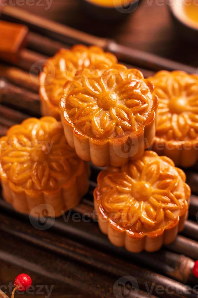 torta di luna di pasticceria tradizionale cinese mooncake con tazze da tè su vassoio di avviso di bambù su sfondo di legno per il festival di metà autunno, primo piano. foto