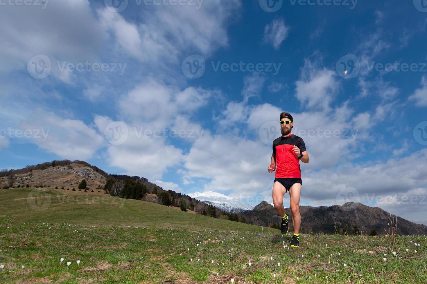 ragazzo con la barba mentre corre in un prato di montagna foto