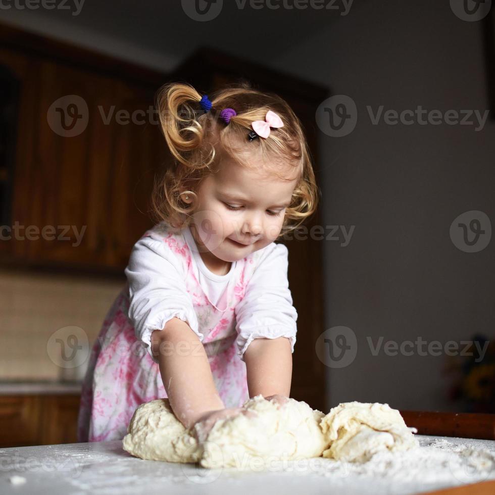 la bambina graziosa che si diverte impasta la pasta foto