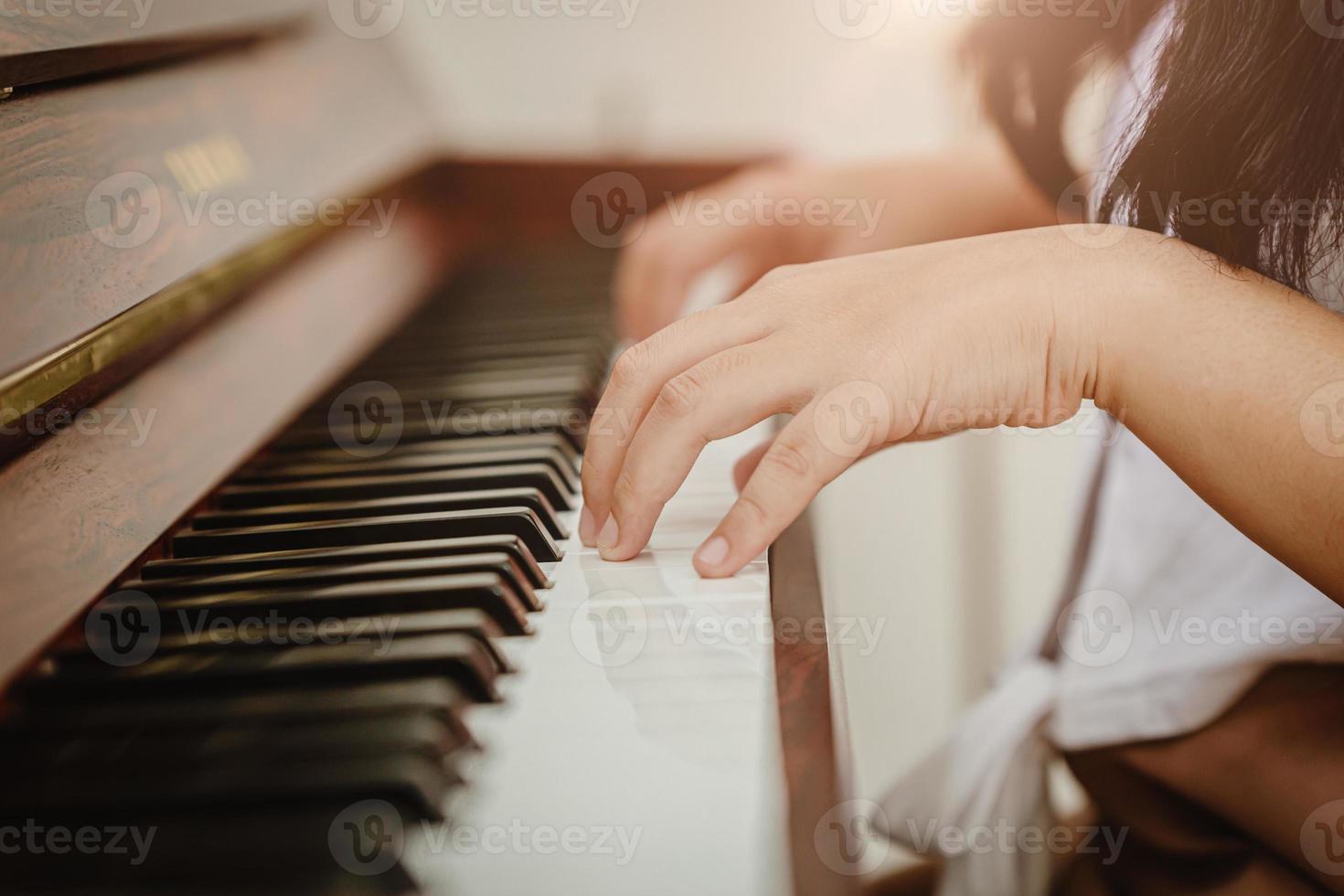 primo piano mano donna suonare il pianoforte a casa colortone vintage. foto