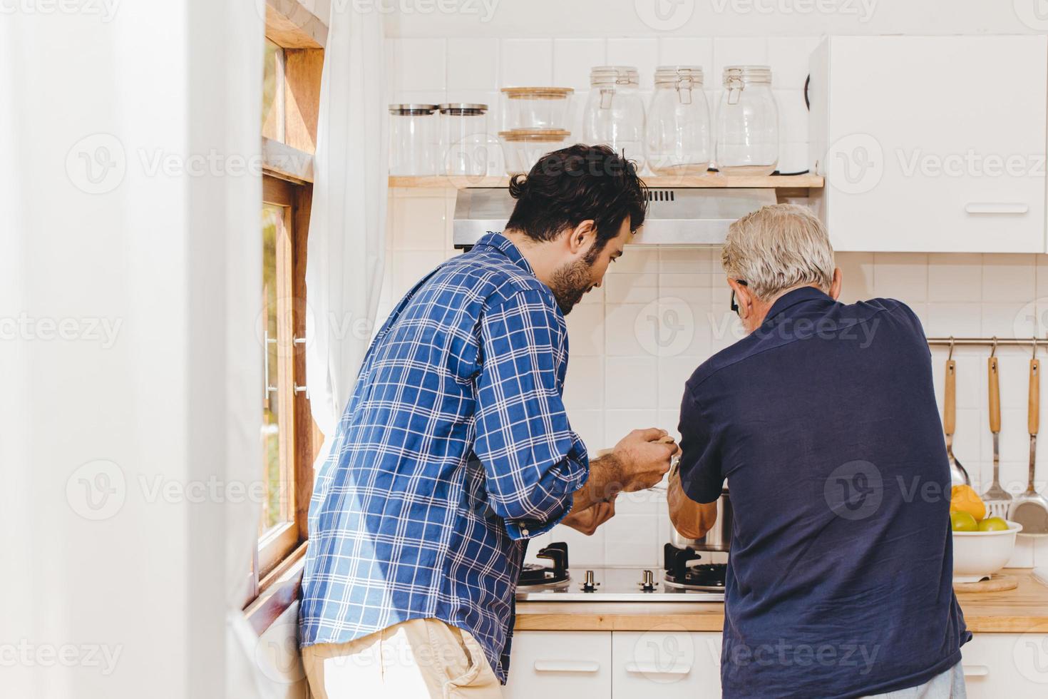 anziano che cucina in cucina con il giovane di famiglia per stare a casa insieme. foto