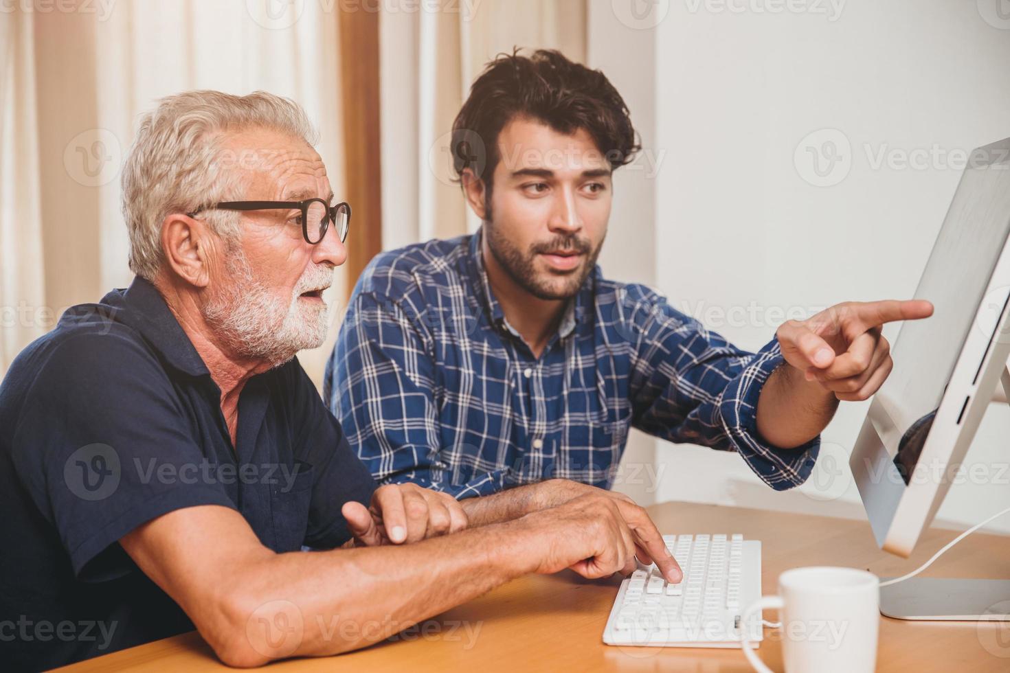 giovane o figlio che insegna a suo nonno anziano papà che impara a usare il computer a casa. foto