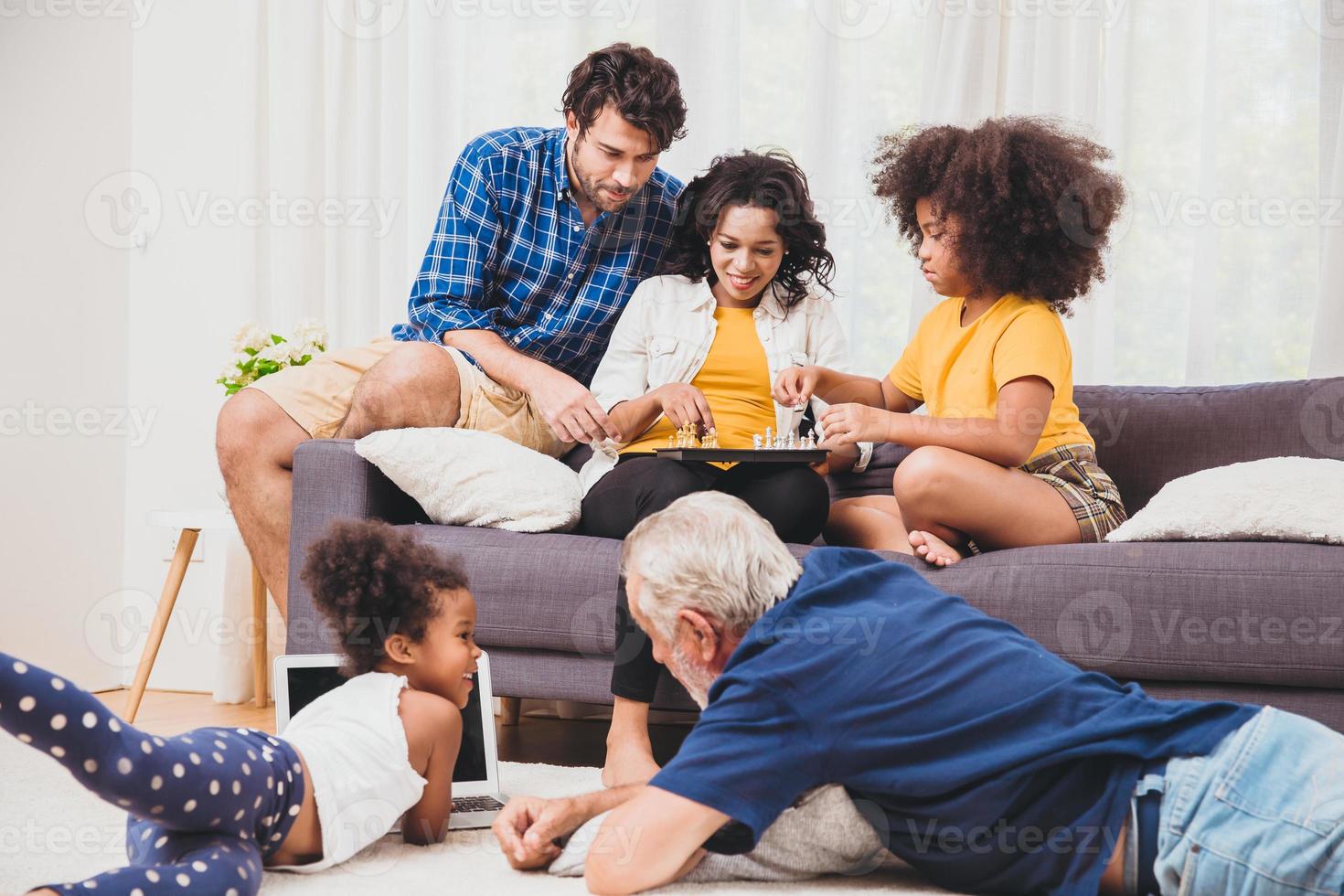 bella casa famiglia stare insieme in soggiorno padre madre e nonno che giocano con la figlia mescolano razza. foto