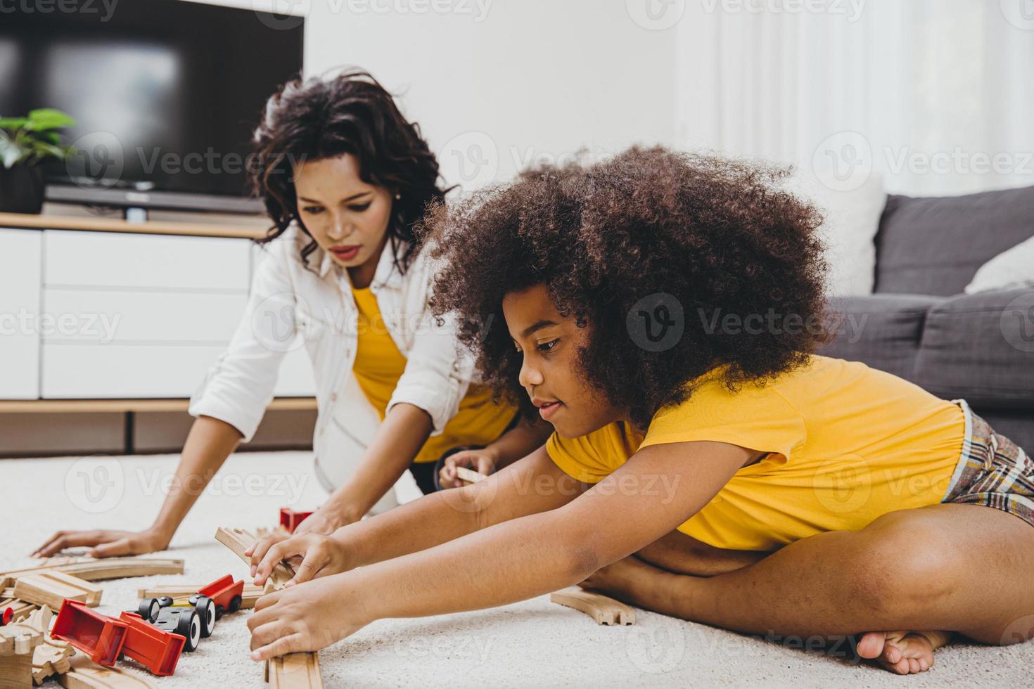 mamma single che vive con due figlie che imparano e giocano a puzzle nell'appartamento di casa. tata che guarda o si occupa dell'infanzia in soggiorno persone di colore. foto