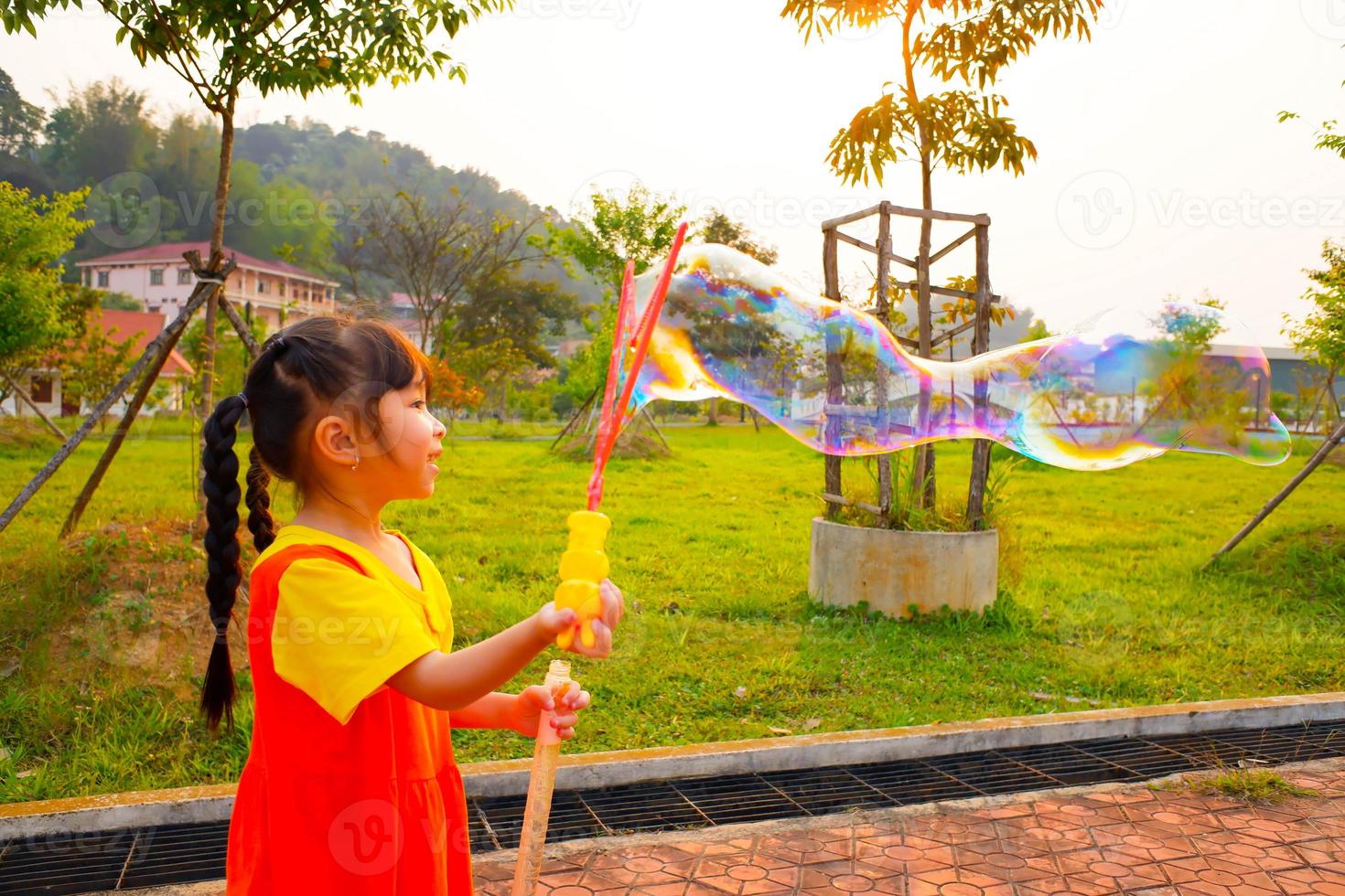 la bella bambina indossa un vestito giallo-arancione, un vestito da gokowa o un mugunghwa che gioca a bolle in un parco pubblico. ragazze e abiti alla moda per adolescenti. foto