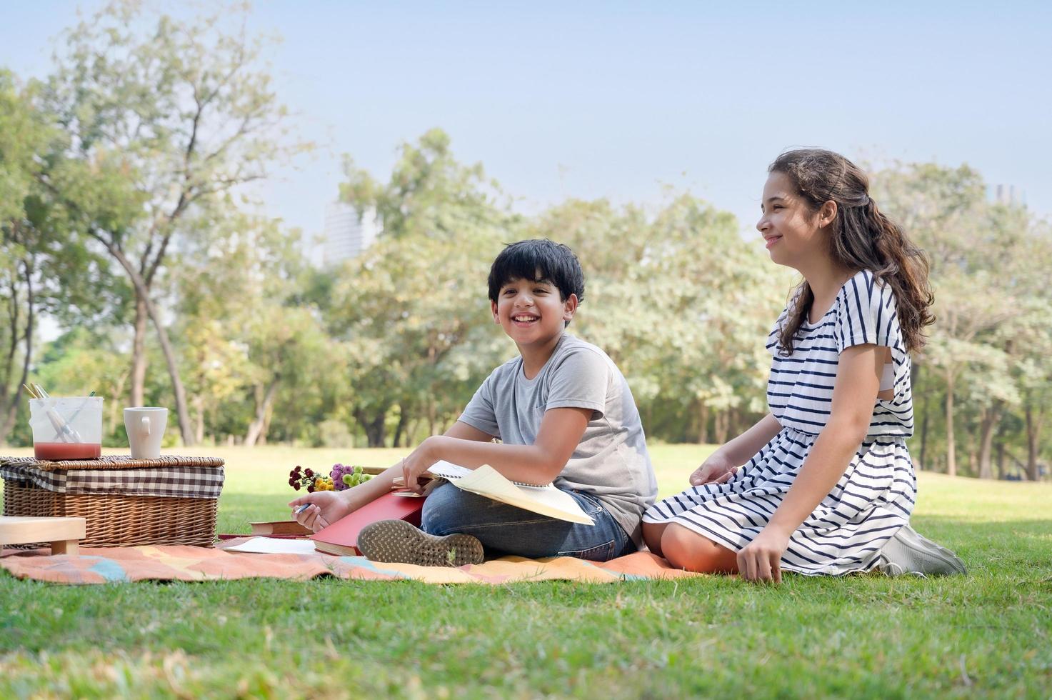 un ragazzo indiano per metà thailandese e una ragazza per metà thailandese europea che imparano fuori dalla scuola nel parco foto