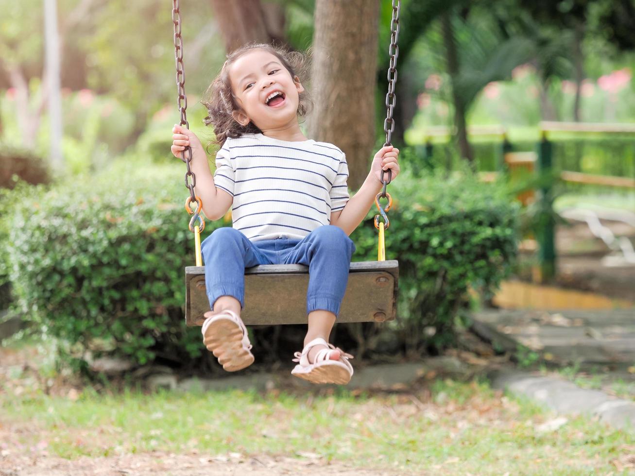 una bella ragazza asiatica stava giocando su un'altalena del parco giochi e si stava divertendo foto